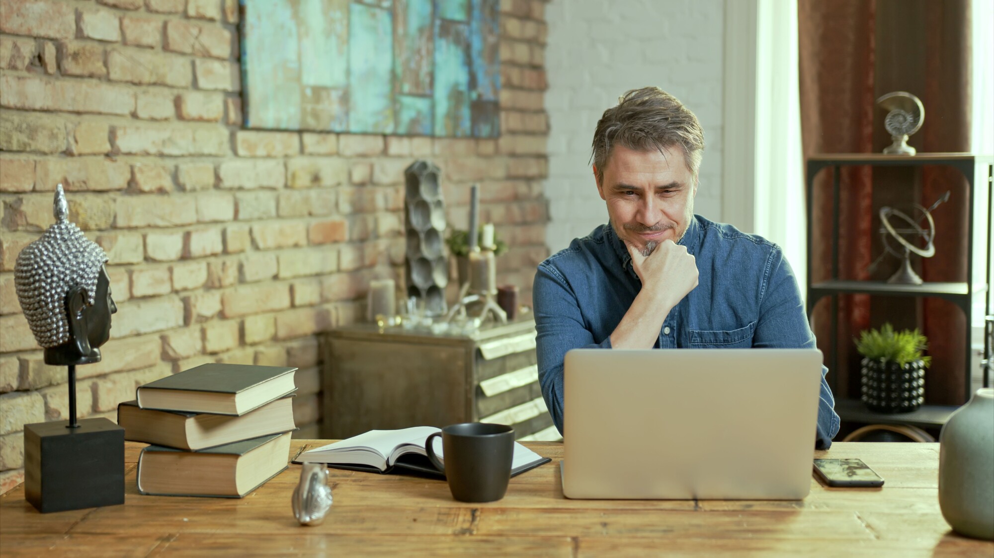 ISA 2026: this image shows a man looking at his laptop and deciding how to invest his ISA.
